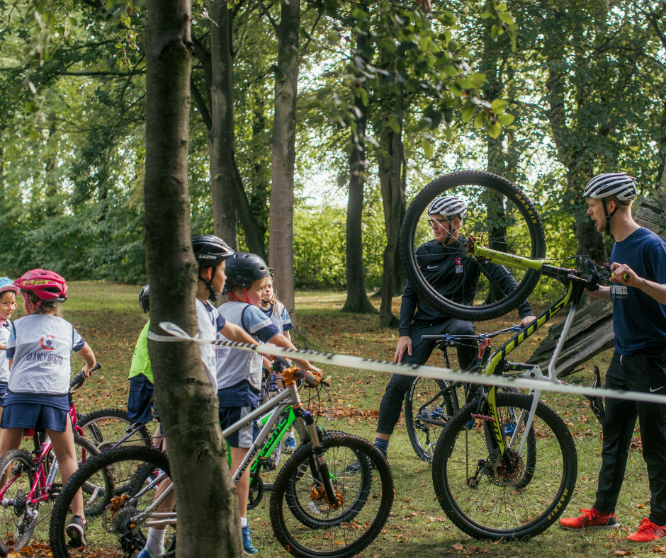 Group of riders and coach in woodland, enjoying the outdoors on their bikes.